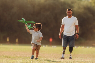 Obraz premium Active, running with toy plane. The amputee father is with his son on the field