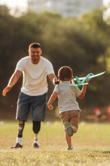 Obraz premium Bright sunlight, illuminated by it. The amputee father is with his son on the field