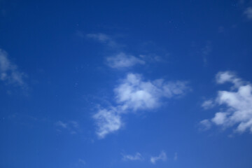 Mystical night sky with soft clouds and dim stars.