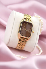 Closeup minimal fashion wristwatch for women on pink background.