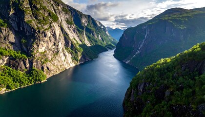 Aerial view of a fjord with towering, rocky cliffs and lush green foliage under a cloudy sky