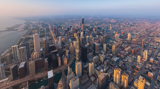 Aerial view of sun-kissed skyscrapers pierce the skyline, casting long shadows across the city's vibrant grid, revealing the iconic John Hancock Center, Chicago, Illinois, United States.
