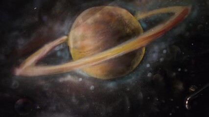 Camera video of painted space scene featuring ringed planet
