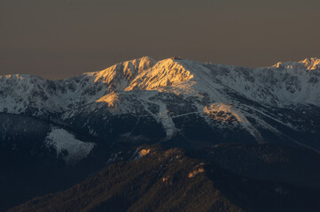 Aerial view of snow-capped mountains touched by the warm glow of the setting sun, Tri Kopy, Zilina Region, Slovakia.