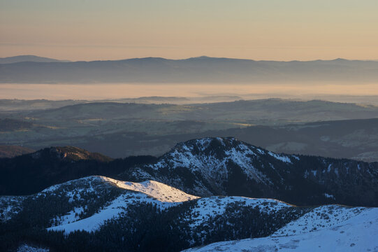 Aerial view of snow-dusted peaks of Tri Kopy bask in the soft, diffused light, casting long shadows across the serene landscape, Zapadne Tatry, Zilina Region, Slovakia.