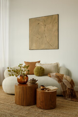 Cozy living room with a cream sofa, warm-toned pillows and wooden tables. Autumn décor and natural...