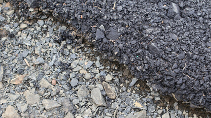 Damaged asphalt road surface with gravel and cracks