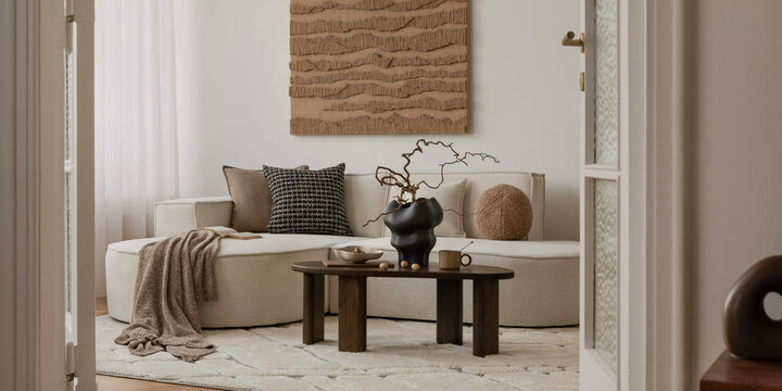 Earthy modern interior with round sofa, minimal coffee table, and large textured wall art in a soft natural palette.