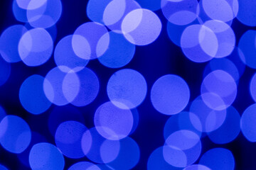 Soft blue Christmas lights create a glowing bokeh background, evoking peace, elegance, and a serene winter holiday mood.