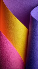 Vibrant rolls of textured paper in shades of purple, orange, yellow, and pink displayed artistically across a surface
