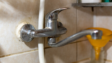 old dirty kitchen faucet with plaque and water connection pipes. broken old plumbing, homemade...