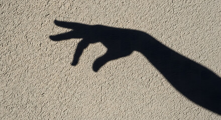 Dark shadow of a human hand and arm projected onto a textured st