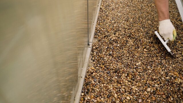 Worker applying resin bound gravel surface by hand
