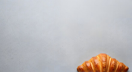 Freshly baked golden croissant pastry on a light gray speckled s