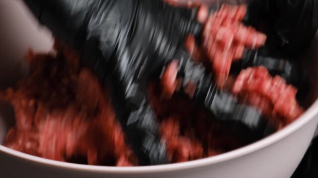 Chef hand kneads and mixes raw beef or lamb mince in a deep bowl. Cooking halal minced food for Ramadan. Bright fresh red mince prepared for traditional national Muslim cuisine.