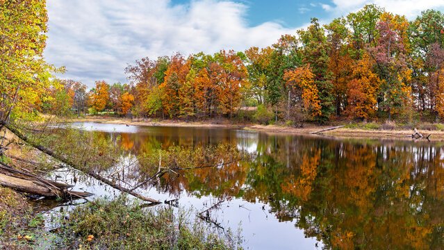 A lake at Quail Ridge Park in Wentzville, Missouri reflects colorful Fall foliage surrounding it
