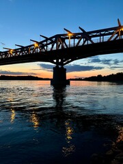Fototapeta premium Bridge over a calm river at sunset with reflections.
