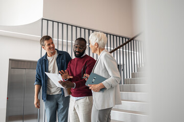Professional Group Discussing Documents in Modern Office Lobby, Collaborative Meeting and Friendly Interaction