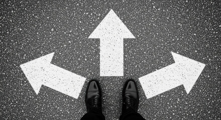 A pair of black shoes stand at a crossroads with three white arrows painted on the asphalt, symbolizing decision making and strategic direction on the road ahead.