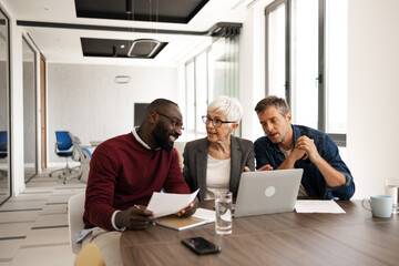 Collaborative Office Meeting With Laptop and Documents Among Team Members