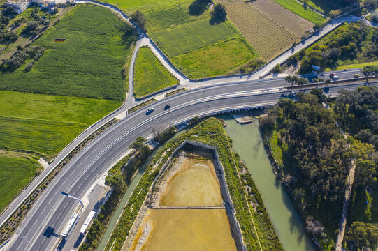Aerial view of the blend of golden earth meeting lush green fields and the urban roads near the coast, Bugibba, St. Paul's Bay, Malta.