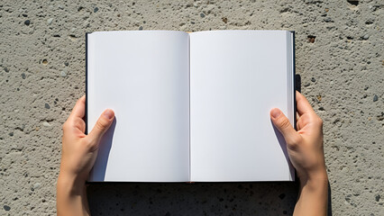 Hands gently cradle an open notebook, its pristine white pages inviting new ideas and stories to be written, set against a stark, textured concrete backdrop