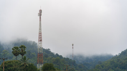 Mobile communication tower rising above misty forested mountains in northern Thailand