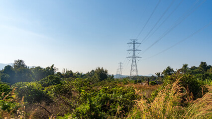 Electricity transmission towers over dry grassland and forest in northern Thailand