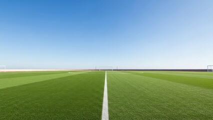 Obraz premium A well-maintained green soccer field with white lines under a clear blue sky on a sunny day.