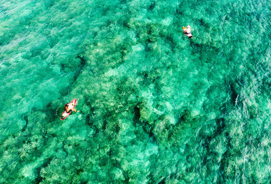 Aerial view of paddleboarders gliding over the translucent turquoise waters near Ala Moana Park and marina, Honolulu, Hawaii, United States.