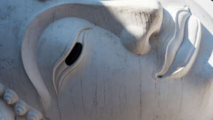 Close up detail of serene Buddha statue face carved in white stone
