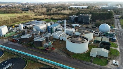 Aerial view of industrial architecture with cylindrical tanks and connecting pipelines casting long shadows in the afternoon light, Milton Keynes, England, United Kingdom.