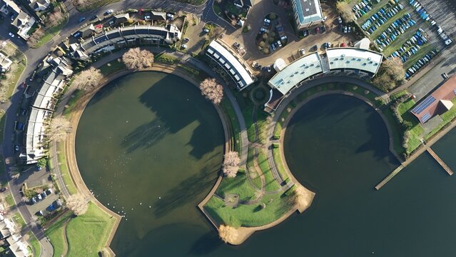 Aerial view of the symmetrical, mirrored curves of the water and buildings reflecting sunlight, creating a harmonious blend of urban design and nature, Milton Keynes, England, United Kingdom.