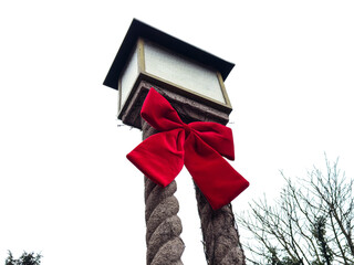 Red bow on twisted rope post with lantern against overcast sky