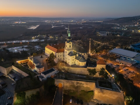 Aerial view of the majestic Nitra Castle illuminated against the fading twilight, its imposing silhouette dominating the landscape, Nitra, Nitriansky kraj, Slovakia.