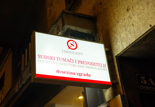 Lingua-Soft sign for court interpreters and translators illuminated at night, showcasing professional services in urban environment with copy space