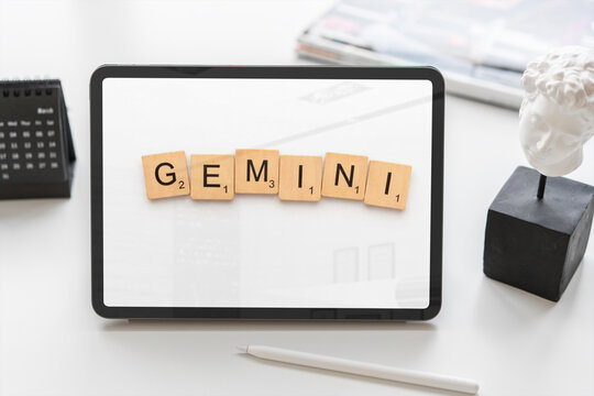 Gemini zodiac sign on tablet screen with scrabble tiles