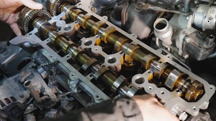 Mechanic's hands install camshaft into engine. Process of reassembling engine after overhaul. Service center specializing in repair of vehicles with internal combustion engines. Reassembling engine.