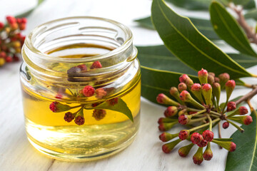 Vibrant fresh clove infused oil in clear glass jar on white