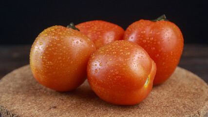 Close up fresh tomatoes on chopping board, isolated black background