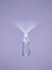 Clear spray bottle dispensing fine mist against a soft purple background
