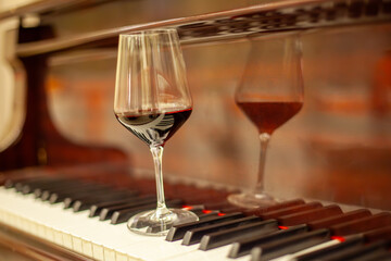 Elegant glass of red wine on the keys of a classical piano. Romantic, sophisticated atmosphere for a concert, celebration, or luxurious evening.