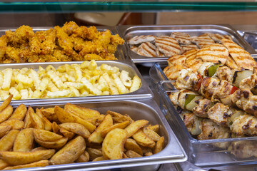 Hot Buffet Counter with Grilled Chicken, Fried Potatoes and Crispy Breaded Meat, Fresh Ready-to-Eat Food in Restaurant Cafeteria