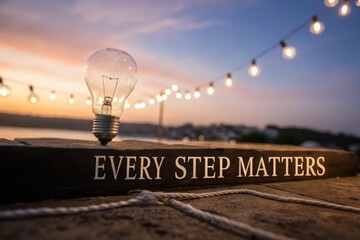 Light Bulb Raised to Sky with Quote Every Step Matters at Sunset