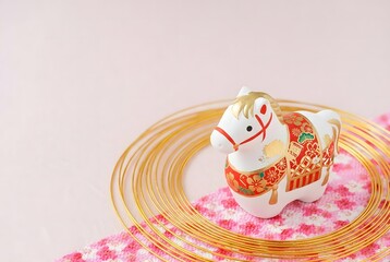 Decorative horse figurine on pink plate isolated on white background