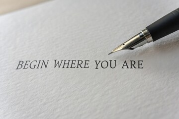 Pen Writing Quote 'Begin' on Blank Page in Close-Up View