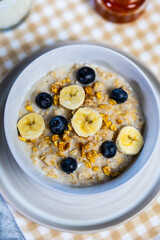 Healthy oatmeal bowl with banana, blueberries and honey drizzle