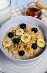 Healthy oatmeal bowl with banana, blueberries and honey drizzle
