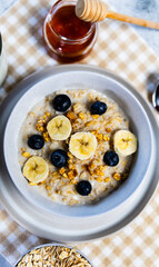 Healthy oatmeal bowl with banana, blueberries and honey drizzle