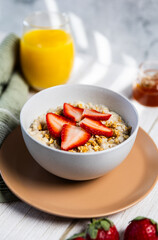 Oatmeal bowl with strawberries granola and orange juice